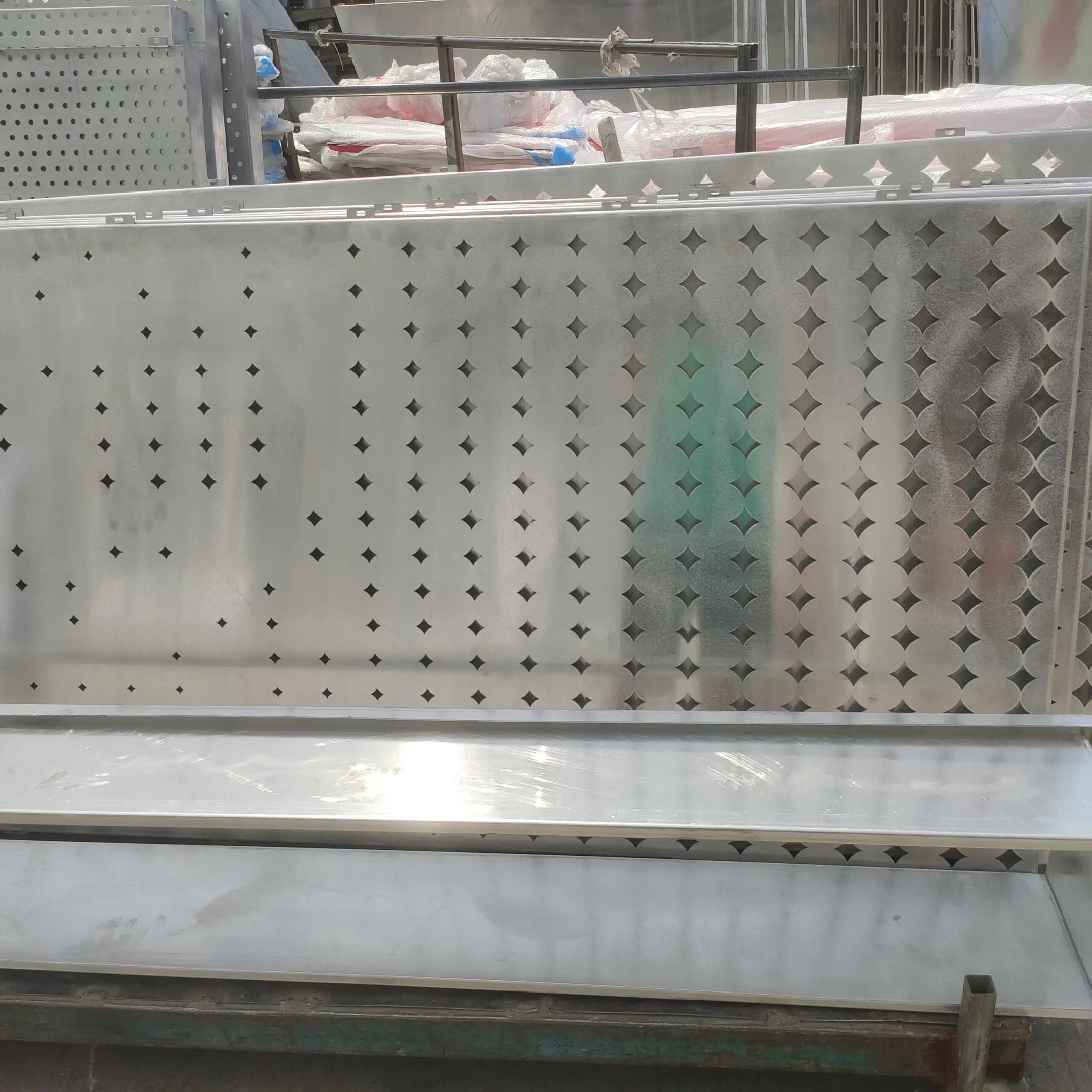 Perforated aluminum cladding panels at Meterny’s factory, ready for surface coating. These laser-cut panels feature unique perforation designs for architectural facades.