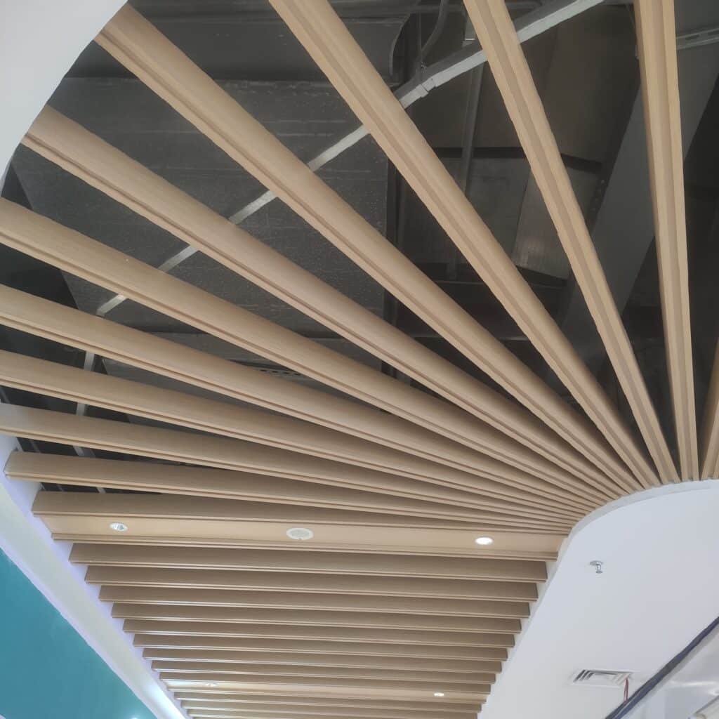 Aluminum tubes ceiling in malls with teak wood grain finish, providing a stylish and modern architectural design.